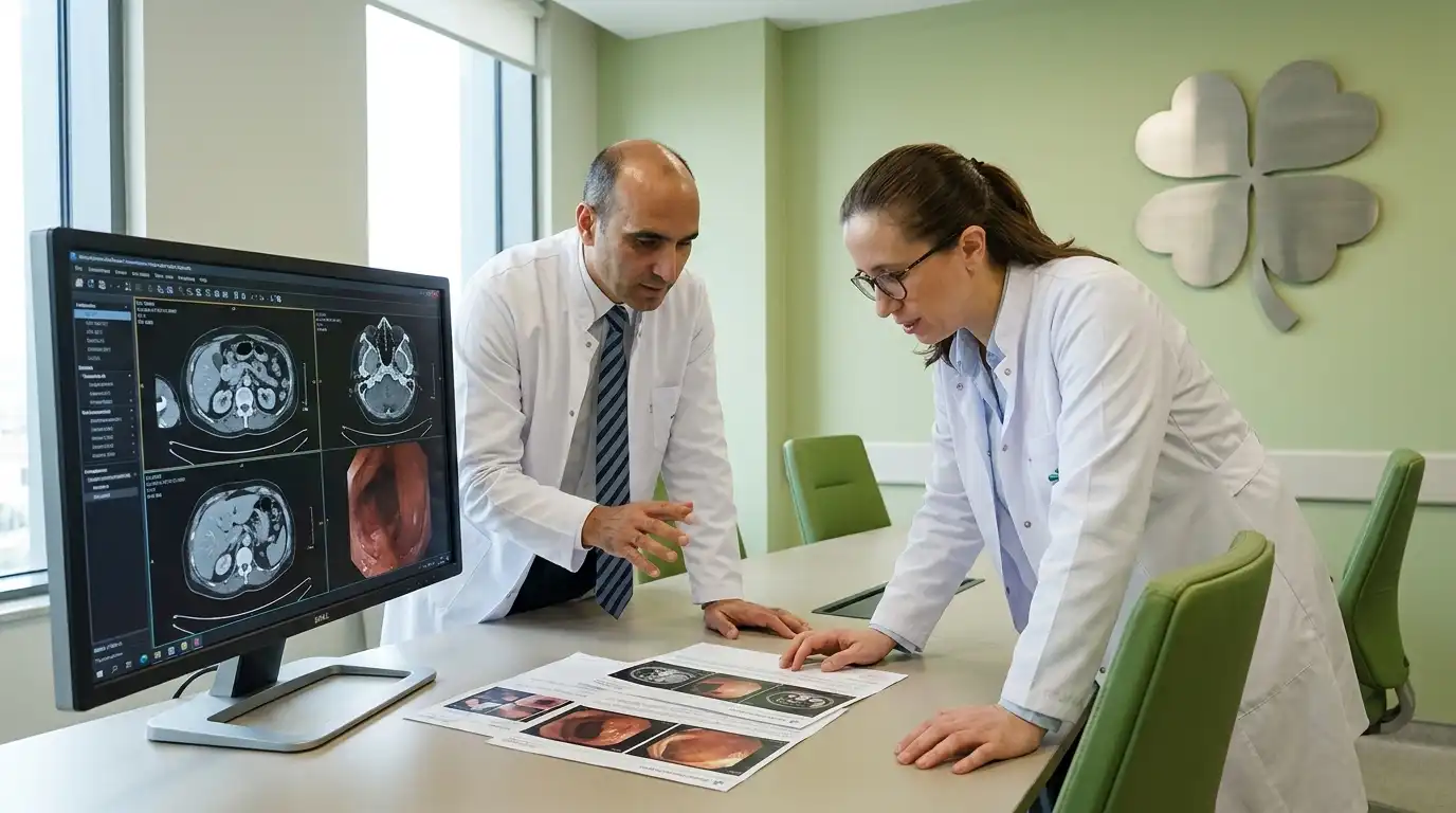Two doctors reviewing CT imaging and endoscopy staging reports together on a monitor in a green clinic office with a four-leaf clover wall decoration